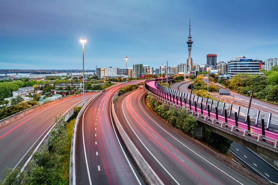 Auckland Sky Tower and motion blurred highway traffic lights during twilight. Illuminated Light Path Bicycle Lane beside the Highway. Auckland City, New Zealand.